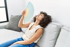 donna con ventaglio soffre il caldo in casa